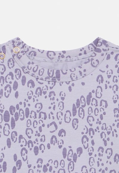 T-shirt roxo de manga curta com uma base de lavanda clara, apresentando um padrão de estampa de leopardo e botões de tom dourado na gola.