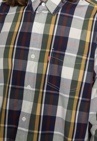Camicia a quadri in tessuto di cotone, con righe blu, verde, giallo e marrone, dotata di colletto button-down e dettaglio della tasca.