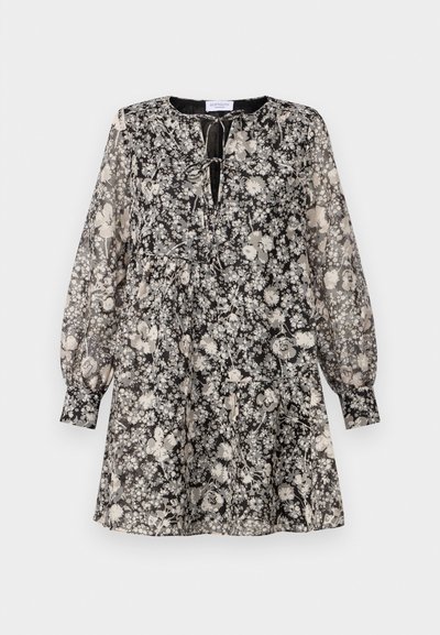 Haljina s cvjetnim uzorkom u crno-bijeloj boji, dugim napuhanim rukavima, okruglim izrezom i detaljem s vezanjem sprijeda; tkanina izgleda lagana i prozirna.