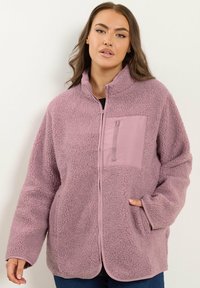 Chaqueta de forro polar rosa claro con cuello alto, cremallera completa y un bolsillo con cremallera en el pecho. Presenta una tela texturizada y bolsillos laterales.