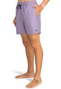 Costume da bagno viola in tessuto leggero, dotato di una vita elastica con cordino, tasche laterali e un'etichetta nera sul orlo.