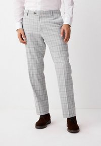 Pantaloni a quadri grigi con vestibilità slim, caratterizzati da una parte frontale piatta, passanti per la cintura e chiusura a un bottone. Indossati con scarpe in suede marroni.