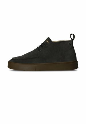 Schwarzer Wildleder-Halbschuh bis zum Knöchel mit brauner Gummisohle, Schnürsenkeln und einer Zuglasche hinten, von der Seite auf weißem Hintergrund gezeigt.