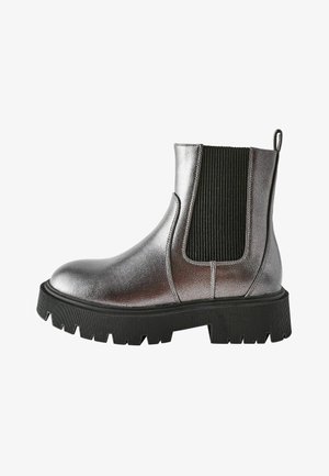 Metallisch silberner Knöchelstiefel mit elastischen Seitenpaneelen, runder Zehenform und einer dicken schwarzen Gummisohle mit strukturiertem Profil.