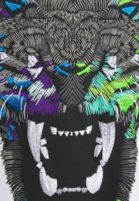 Embroidered textile featuring a black base with a colorful wolf design. Threads in silver, blue, green, and purple create detailed fur patterns.