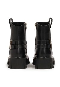 Černé kožené kotníkové boty s matným povrchem, vybavené dvěma kovovými přezkami, zipem na zapínání a silnými rozšířenými podrážkami.