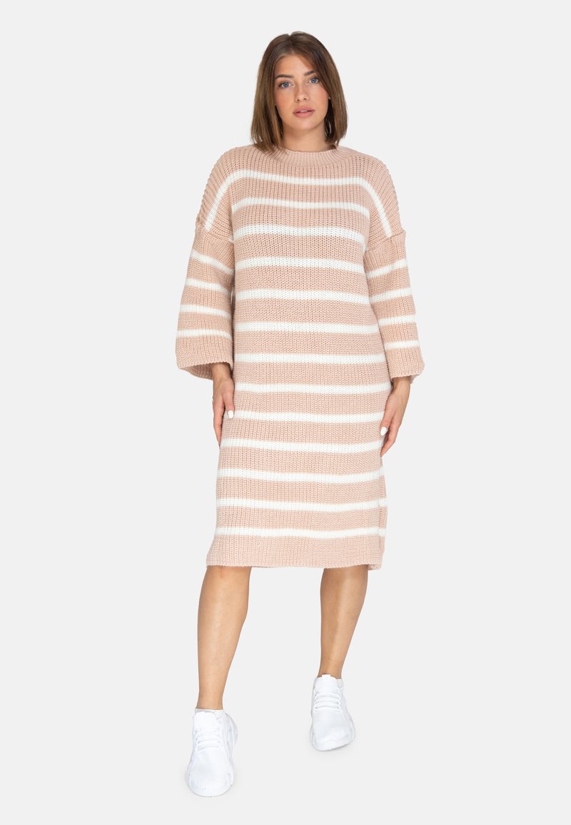 Strickkleid in zartem Rosa mit breiten weißen Streifen, verfügt über eine lockere Passform, übergroße Ärmel und einen runden Ausschnitt. Kombiniert mit weißen Sneakers.