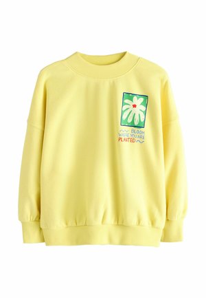 Gelber Pullover mit einem gerippten Kragen und Bündchen. Mit einem grafischen Design einer Blume und dem Text: "BLOOM WHERE YOU ARE PLANTED."