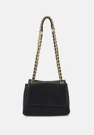 Sac à épaule en cuir noir avec bandoulière chaîne dorée et noire et fermeture à rabat sur fond uni.