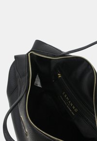 Borsa nera con texture e cerniera dorata. L'interno presenta una fodera in tessuto nero e un compartimento con cerniera etichettato "ERMANNO."