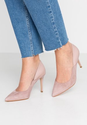 Różowe szpilki z noskiem w kolorze różowym, wykończone zamszem, z gładką skórzaną tylną częścią. Posiadają smukły obcas stiletto oraz zwężający się kształt palców.