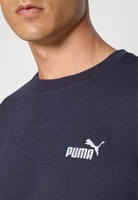 Navy blue sweatshirt with a crew neck, made of cotton. Features a white embroidered Puma logo on the chest. Soft texture and subtle finish.