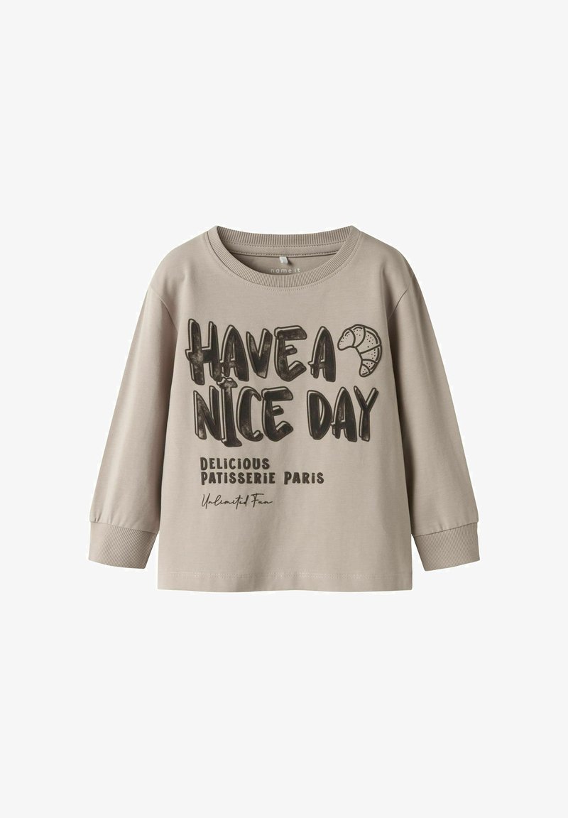 Light beige long-sleeve T-shirt made of cotton; features black text: "HAVE A NICE DAY" and "DELICIOUS PATISSERIE PARIS" with a croissant graphic.
