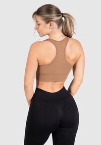 Bruine geribbelde sportbeha met een racerback ontwerp, gecombineerd met hoge zwarte legging. Soepele textuur en aansluitende silhouet.