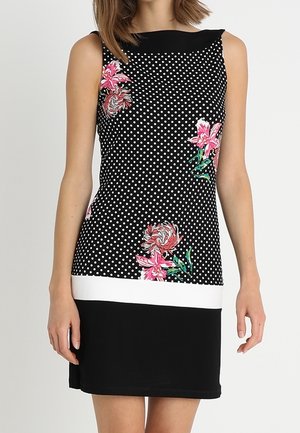 Robe noire sans manches avec des pois blancs, des imprimés floraux roses, une bande horizontale blanche et une jupe noire unie.
