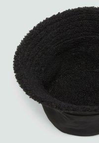 Chapeau seau rond noir avec un extérieur en polaire texturée et un intérieur lisse. Doté d'un large bord doux et d'une couronne structurée.