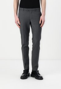 Szürke, sima textrű, slim fit szabású nadrág, övbújtatókkal, fekete cipőkkel párosítva. Az anyaga könnyűnek és struktúrált kinézetűnek tűnik.