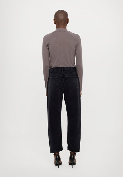 Grijze longsleeve top gecombineerd met hoogwaisted zwarte denim jeans. De jeans zijn losjes passend, met zijvakjes en een lichte textuur.
