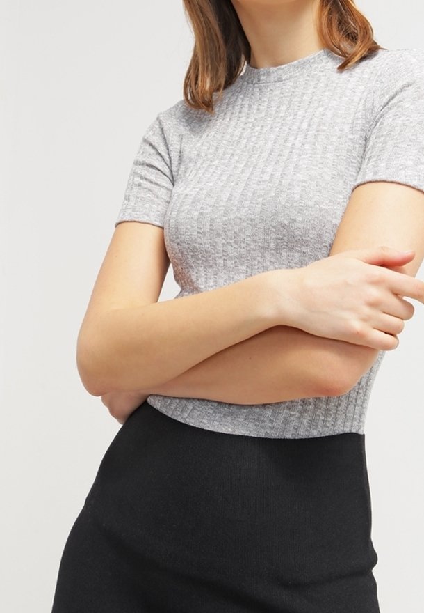 Szary prążkowany top z krótkim rękawem i okrągłym dekoltem, zestawiony z czarną spódnicą z wysokim stanem. Miękki materiał o dopasowanym kroju.