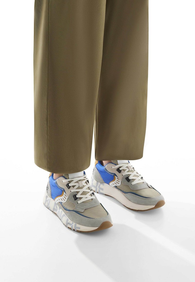 Sneaker sportive grigie e blu con tessuto texturizzato, lacci bianchi e suole spesse con accenti beige e dettaglio del logo sul lato.