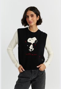 Zwarte gebreide sweater vest met witte mouwen, voorzien van een Snoopy-afbeelding, rode harten en de tekst "Snoopy Est. 1950". Geribbelde halslijn en zoom.