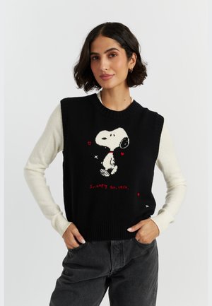 Zwarte gebreide sweater vest met witte mouwen, voorzien van een Snoopy-afbeelding, rode harten en de tekst "Snoopy Est. 1950". Geribbelde halslijn en zoom.
