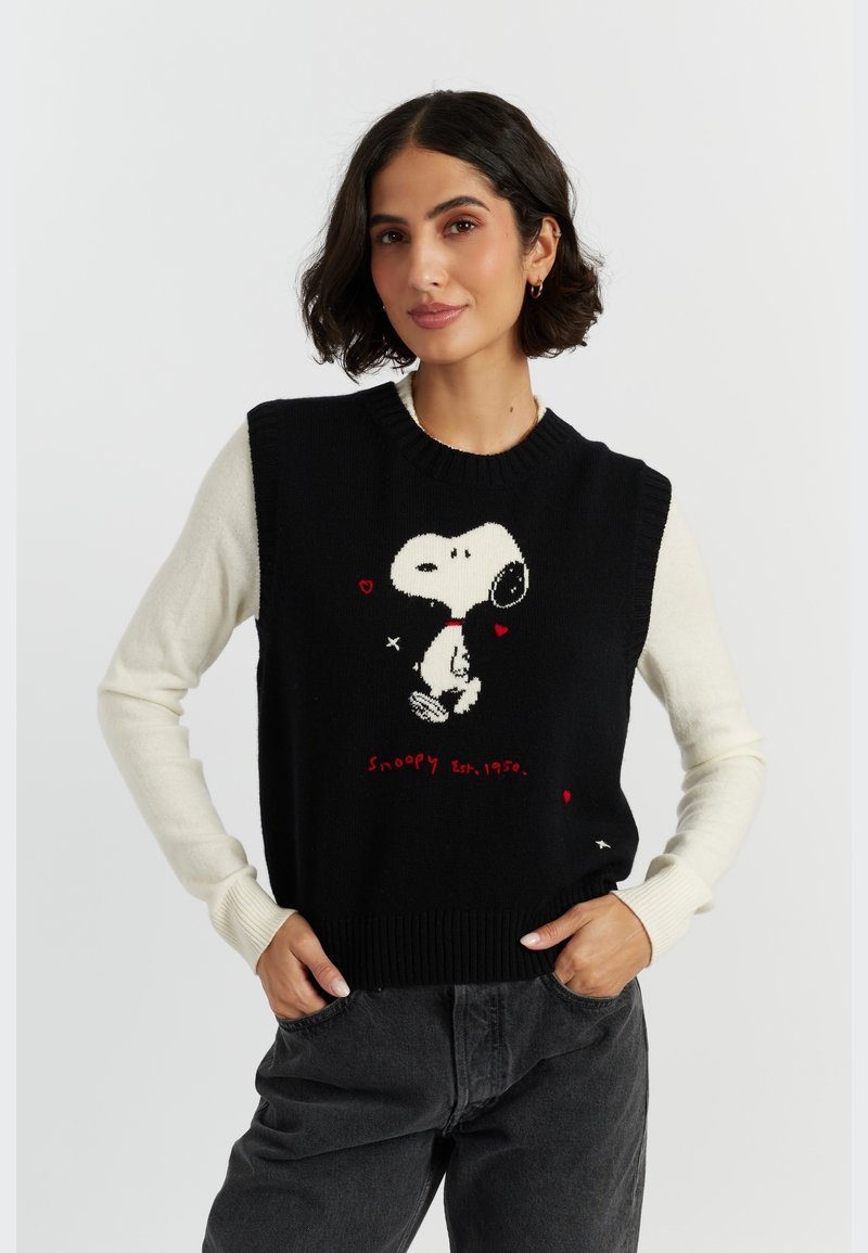Zwarte gebreide sweater vest met witte mouwen, voorzien van een Snoopy-afbeelding, rode harten en de tekst "Snoopy Est. 1950". Geribbelde halslijn en zoom.
