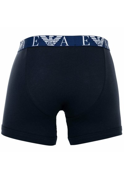 Marineblaue Baumwoll-Boxershorts mit einem gemusterten Gummibund, der ein Logo trägt. Glatte Textur, körpernahe Passform und mittellanger Schnitt bis zum Oberschenkel.