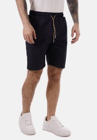 Pantaloni corti blu navy con vita elasticizzata e cordoncino decorativo. Realizzati in un tessuto leggero, presentano tasche laterali.