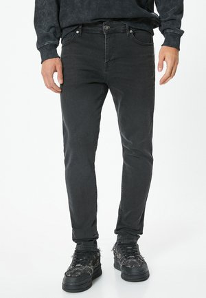 Czarne dżinsy o slim fit z średnim stanem, pięcioma kieszeniami i subtelnym, wyblakłym wzorem. Uzupełnione czarnymi trampkami.