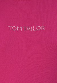 Fuksija majica s rebrasto strukturo; vsebuje logo "TOM TAILOR" iz srebrnih rhinestones. Okrogla ovratnica, sproščen kroj.