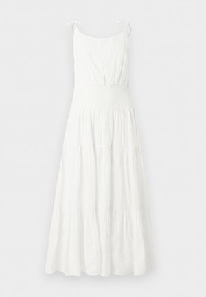 Robe longue blanche sans manches avec taille froncée et jupe à volants, dotée de fines bretelles nouées en nœuds.