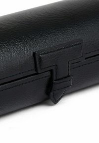 Custodia in pelle nera con una texture liscia, dotata di un evidente dettaglio di chiusura geometrica e di cuciture sottili lungo i bordi.