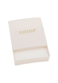 Weißer rechteckiger Karton mit leicht abgerundeten Ecken, auf dem Deckel mit goldener Schrift das Wort "amor". Das Innere ist leer und beige.