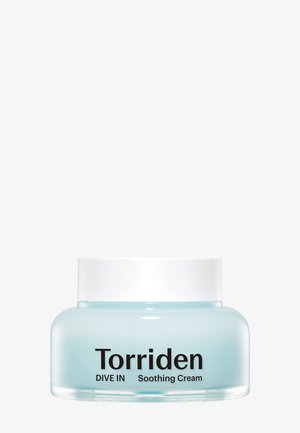 Tarro de vidrio azul claro con tapa blanca, etiquetado "Torriden DIVE IN Crema Calmante" en texto negro en negrita. Superficie suave, forma redondeada.