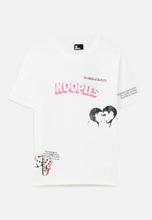 White cotton t-shirt featuring bold pink text "KOOPLES," graphic kiss illustration, and printed quotes on sleeves and hem.