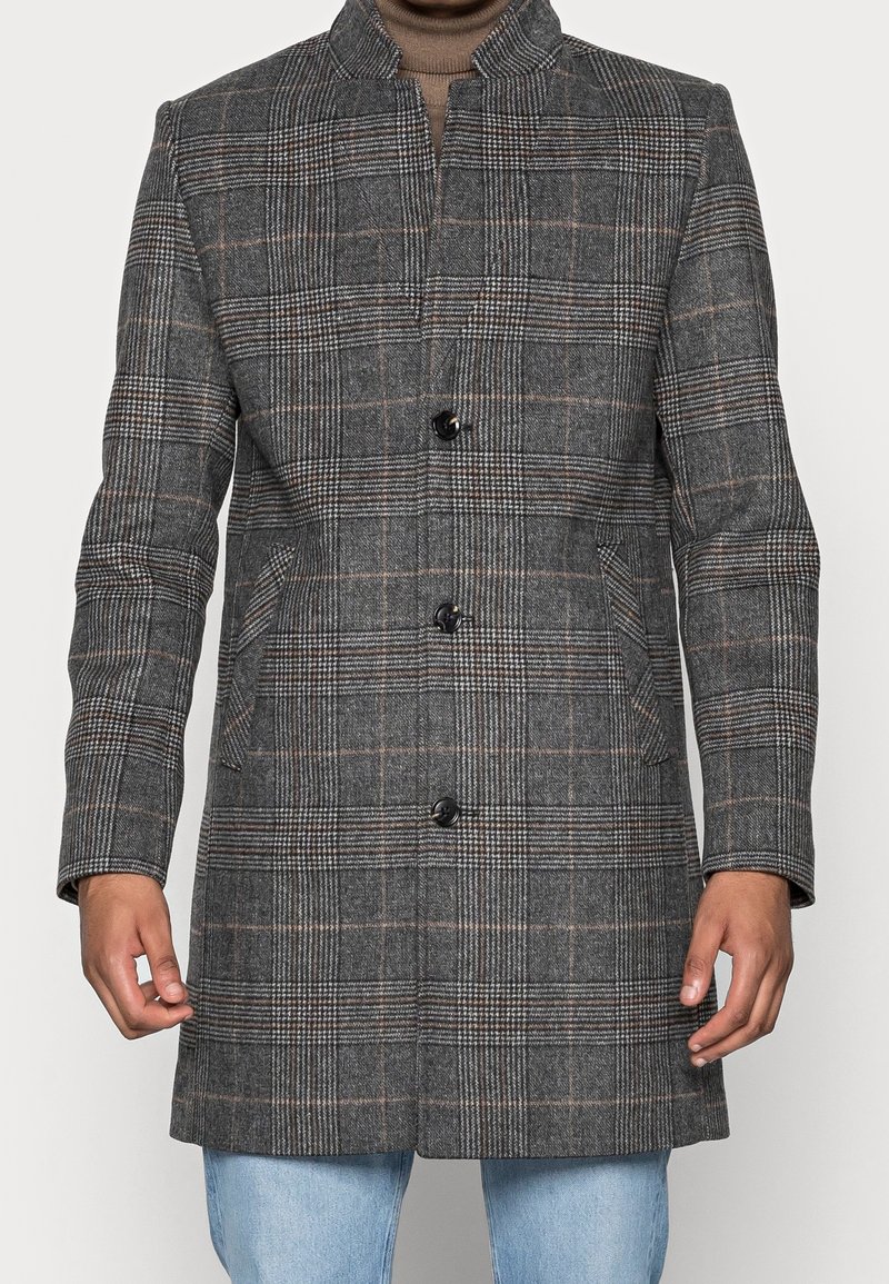 Manteau en tartan gris avec col montant, présentant des boutons noirs, des poches latérales et une coupe ajustée, fabriqué en tissu en laine texturé.