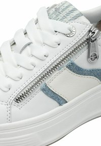 Sneaker bianca con dettagli in denim, dotata di una cerniera laterale e lacci bianchi. La suola è rialzata e texturizzata per garantire una buona presa.