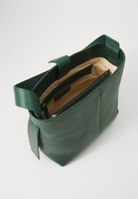 Borsa a mano in pelle verde con una superficie liscia, apertura superiore e interno beige. Caratterizzata da una tasca con zip e manici piatti.
