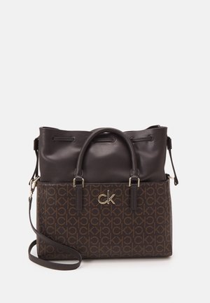 Bolso de mano marrón oscuro con patrón de monograma CK, logo CK dorado, asas cortas y correa de hombro ajustable sobre un fondo liso.