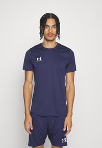 Námornícky atletický set vyrobený z priedušného materiálu, pozostávajúci z trička s krátkym rukávom a šortiek, s bielym logom Under Armour na oboch kusoch.