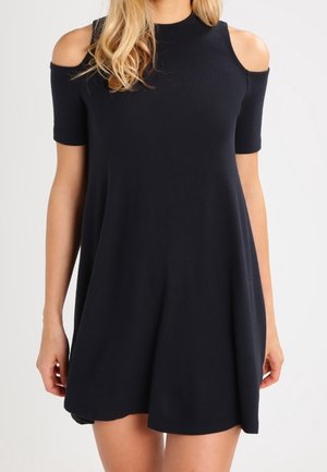 Robe bleu marine à épaules dénudées en tissu doux, avec manches courtes, col haut et silhouette trapèze qui tombe délicatement.