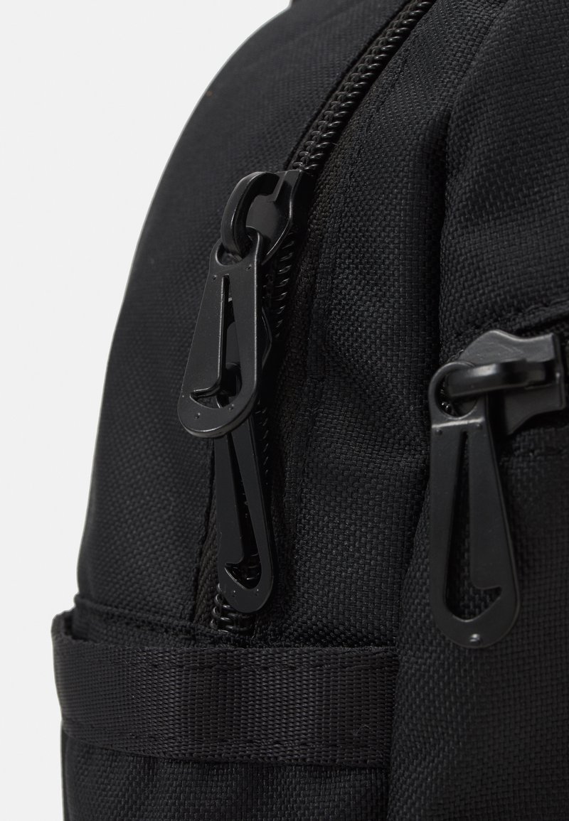 Zaino nero in tessuto con texture liscia, dotato di cerniere doppie e accessori neri. Include spallacci regolabili e una tasca laterale.