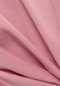 Zacht roze stof met soepele, vloeiende plooien en een fijne, geweven textuur die zachte schaduwen en hoogtes op het oppervlak creëert.