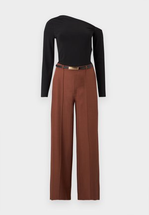 Haut asymétrique noir à manches longues associé à un pantalon marron taille haute à jambes larges et une ceinture noire à boucle dorée.