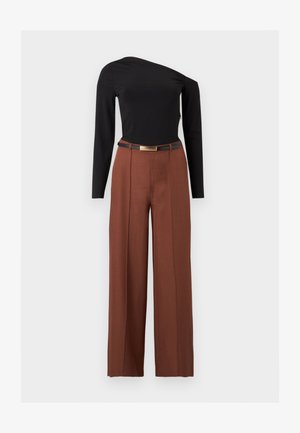 Haut asymétrique noir à manches longues associé à un pantalon marron taille haute à jambes larges et une ceinture noire à boucle dorée.