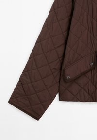 Braune, gesteppte Jackenärmel mit Rautensteppung und einer Knopfklapptasche auf weißem Hintergrund.