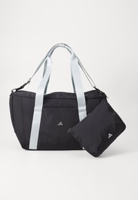 Crna sportska torba s svijetloplavim trakama, izrađena od glatkog materijala. Ima zippered džep pričvršćen, s minimalnim brendingom sprijeda.
