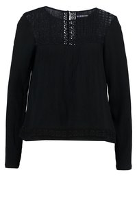 Haut noir à manches longues avec une texture plissée, des détails en dentelle au niveau du col et de l'ourlet, et un col rond. Présente une fermeture à boutons à l'arrière.