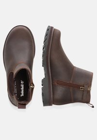 Botas de tobillo de cuero marrón con un acabado suave, cremallera en el lateral y suela de goma texturizada con dibujos profundos para una mejor tracción.